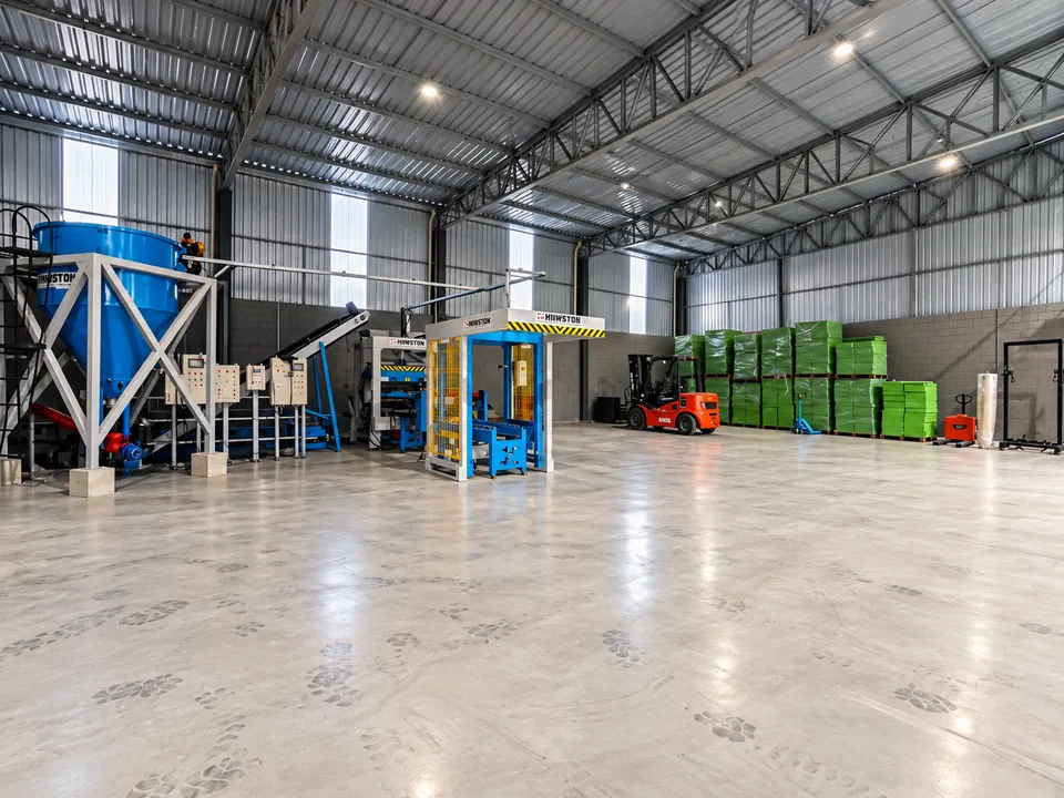Interior do galpão da DanBlock com máquinas, empilhadeira e paletes