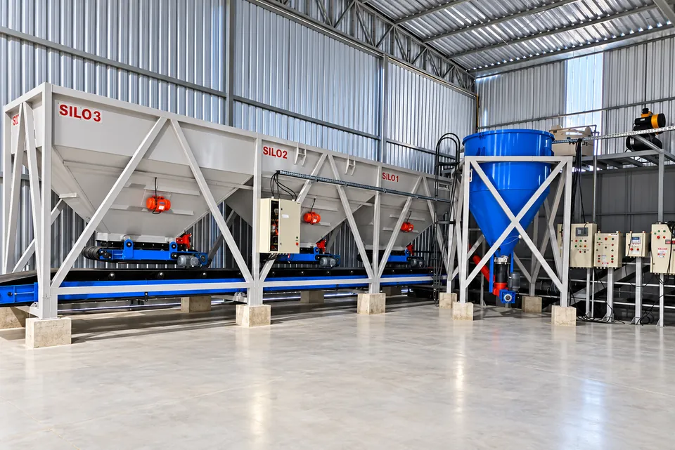 Três silos com esteira transportadora e silo azul no interior do galpão da DanBlock